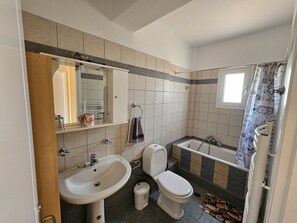 A bathroom with a sink, toilet, and bathtub. - Villa clotho (Markopoulo Mesogaias)