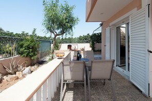 An outdoor patio with a table and chairs, a potted plant, and a tree. - Villa clotho (Markopoulo Mesogaias)