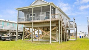 A two-story house with a balcony and a covered porch. - Perfectly SeaSun'd | Steps to Beach + Canal Front! (Surf City)