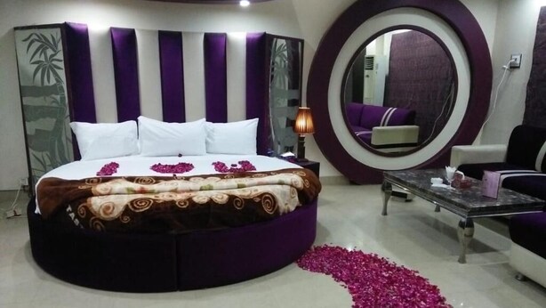 A circular bed with a patterned bedspread, a large mirror, and a decorative mirror frame. - Fair Mont (Multan)