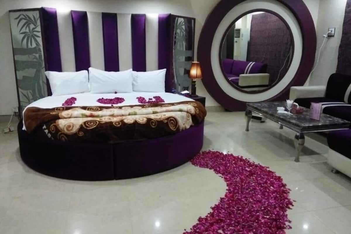 A circular bed with a patterned bedspread, a large mirror, and a decorative mirror frame.