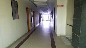 A long, narrow hallway with doors on both sides, leading to a bright area at the end. - Fair Mont (Multan)
