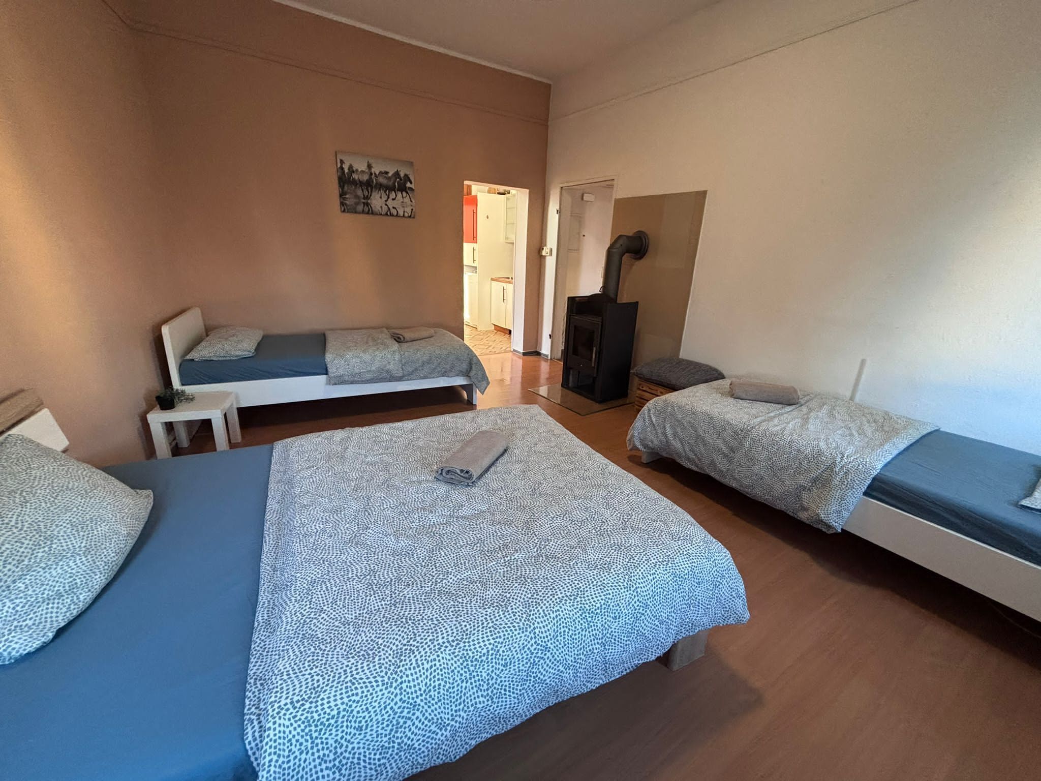 A room with two beds, a small table, and a fireplace.
