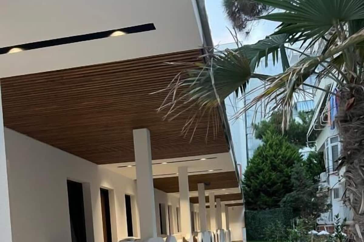 Un bâtiment moderne doté d’une galerie couverte, de murs blancs et d’un plafond en bois.