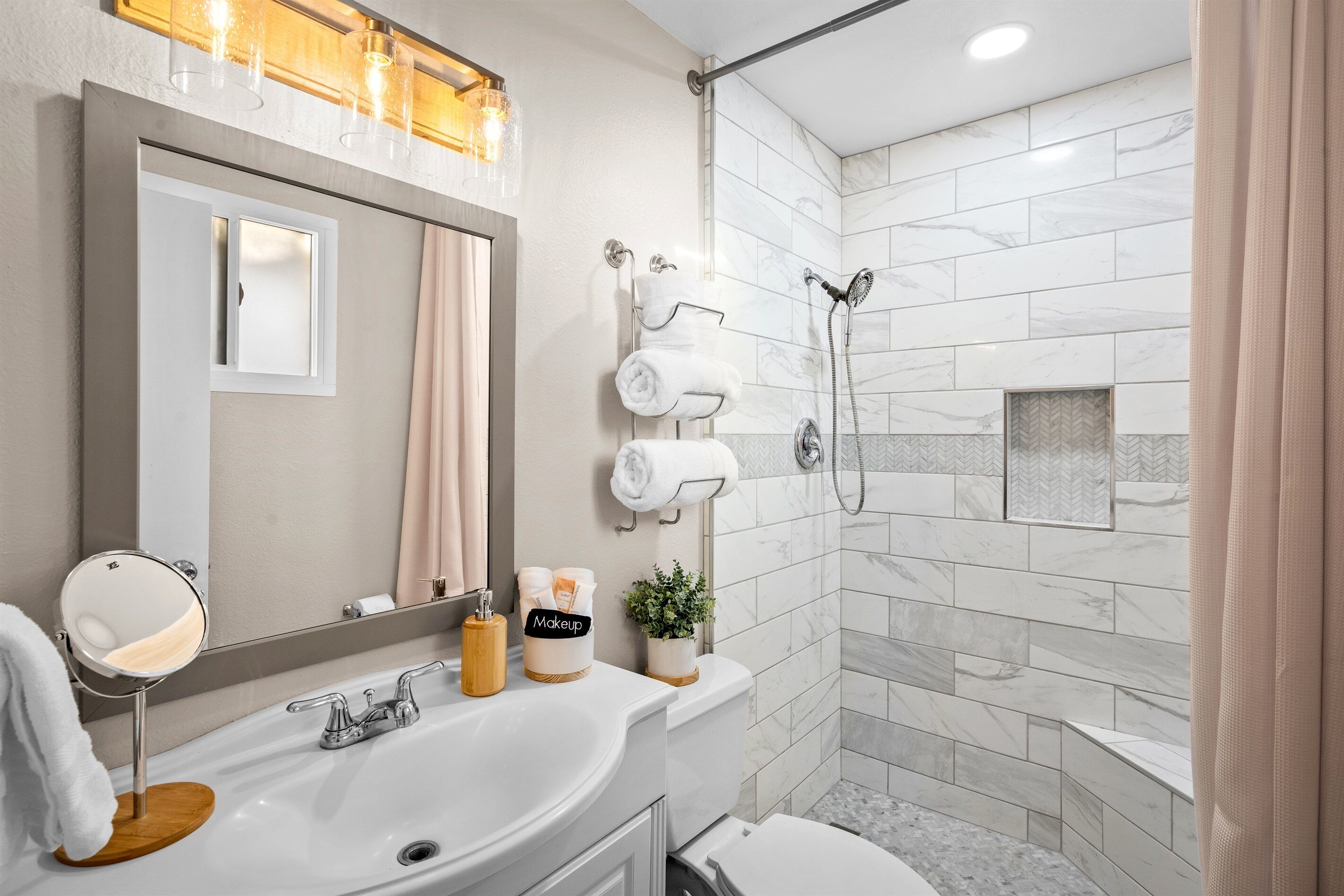 Un baño moderno con un espejo grande, un lavabo, una ducha y un inodoro.