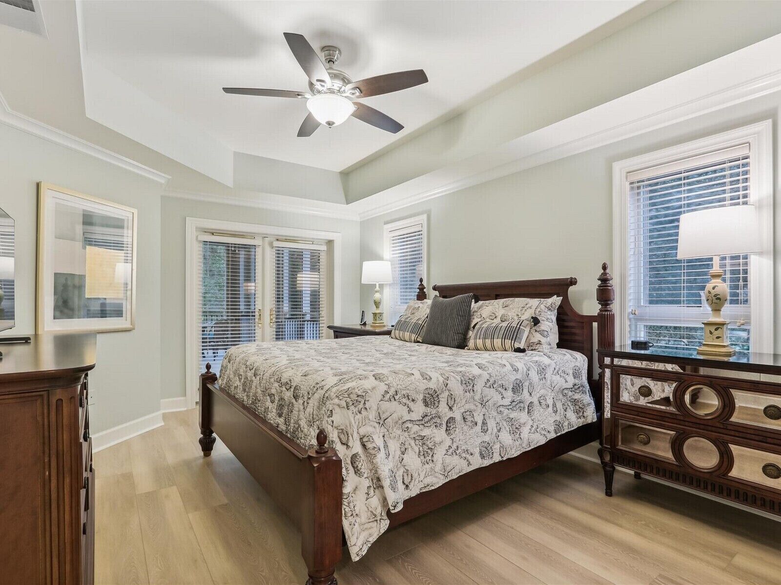 A bedroom with a bed, a ceiling fan, a dresser, and a window with blinds.