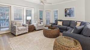 Ein Wohnzimmer mit grauem Sofa, zwei Sesseln, einem Couchtisch und einem Deckenventilator.