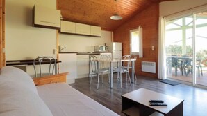 A cozy room with a wooden ceiling, a dining area with a table and chairs, a kitchenette, and a sliding glass door leading to an outdoor area with a deck.