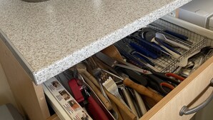Una cocina con microondas, ollas y un cajón con utensilios.