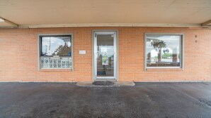 A brick building with a glass door and windows, a concrete ground, and a small awning.