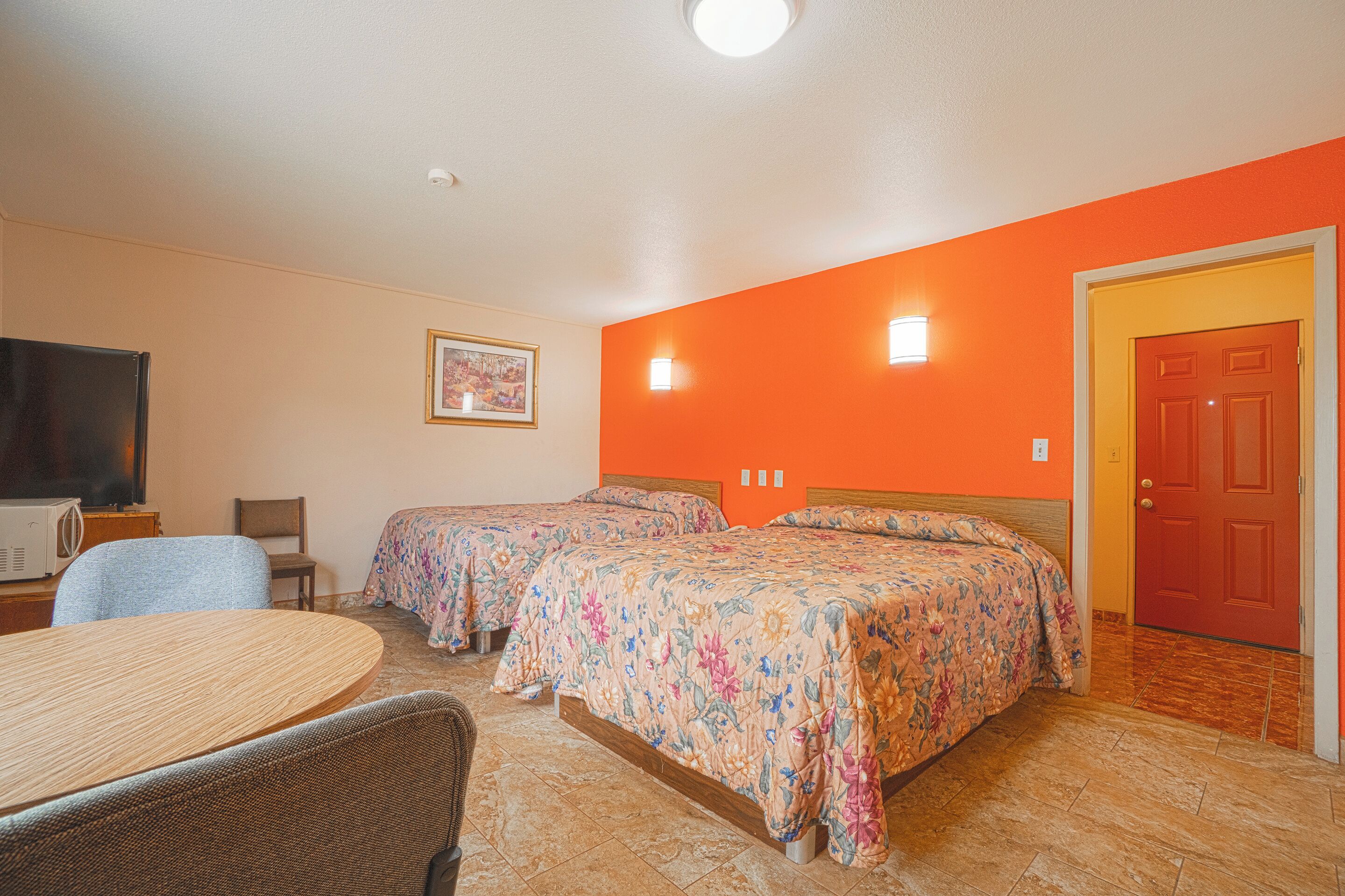 A room with two beds, a dining table, and a television.
