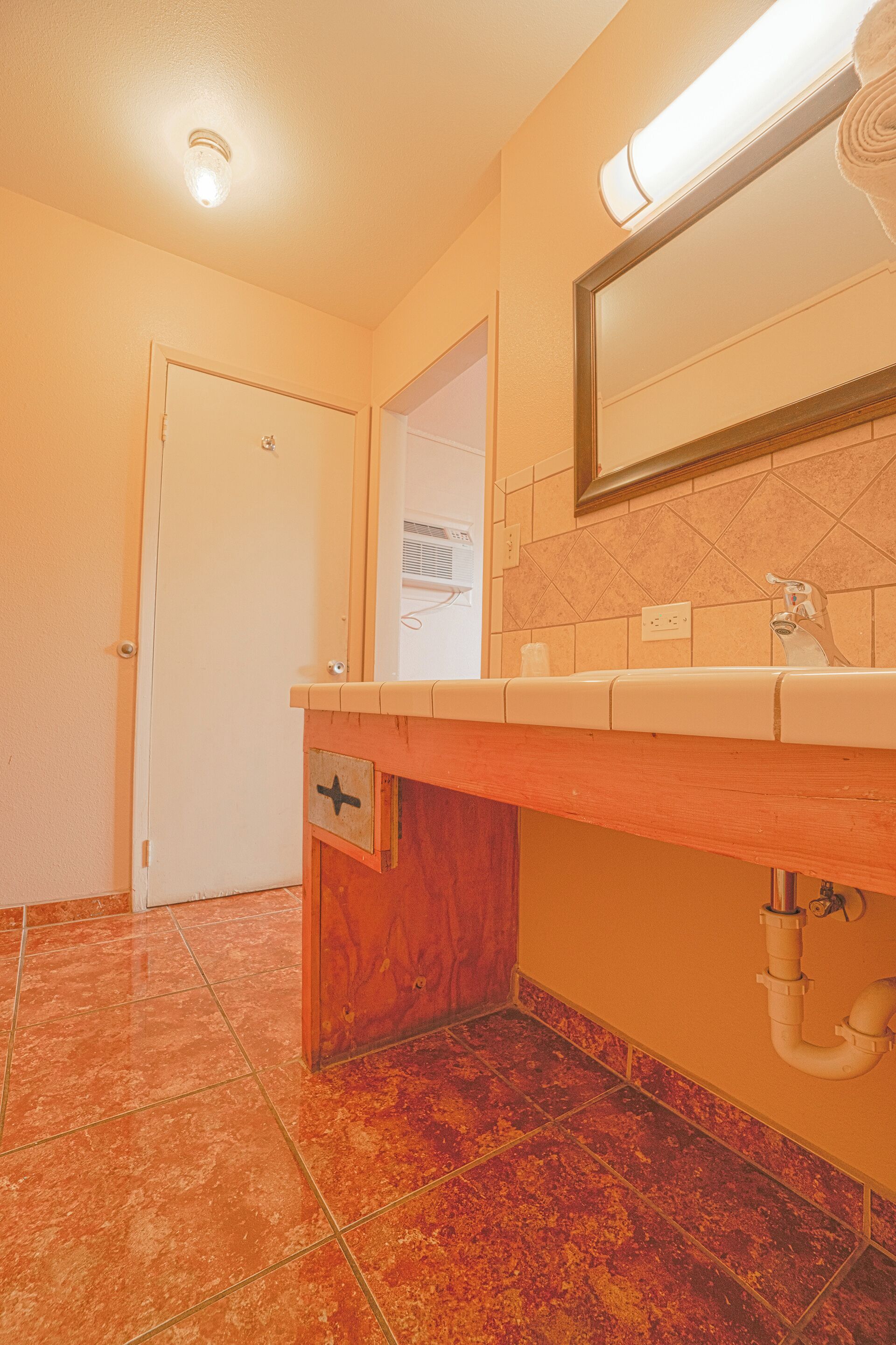 A bathroom with a wooden vanity, a mirror, and a tiled floor.