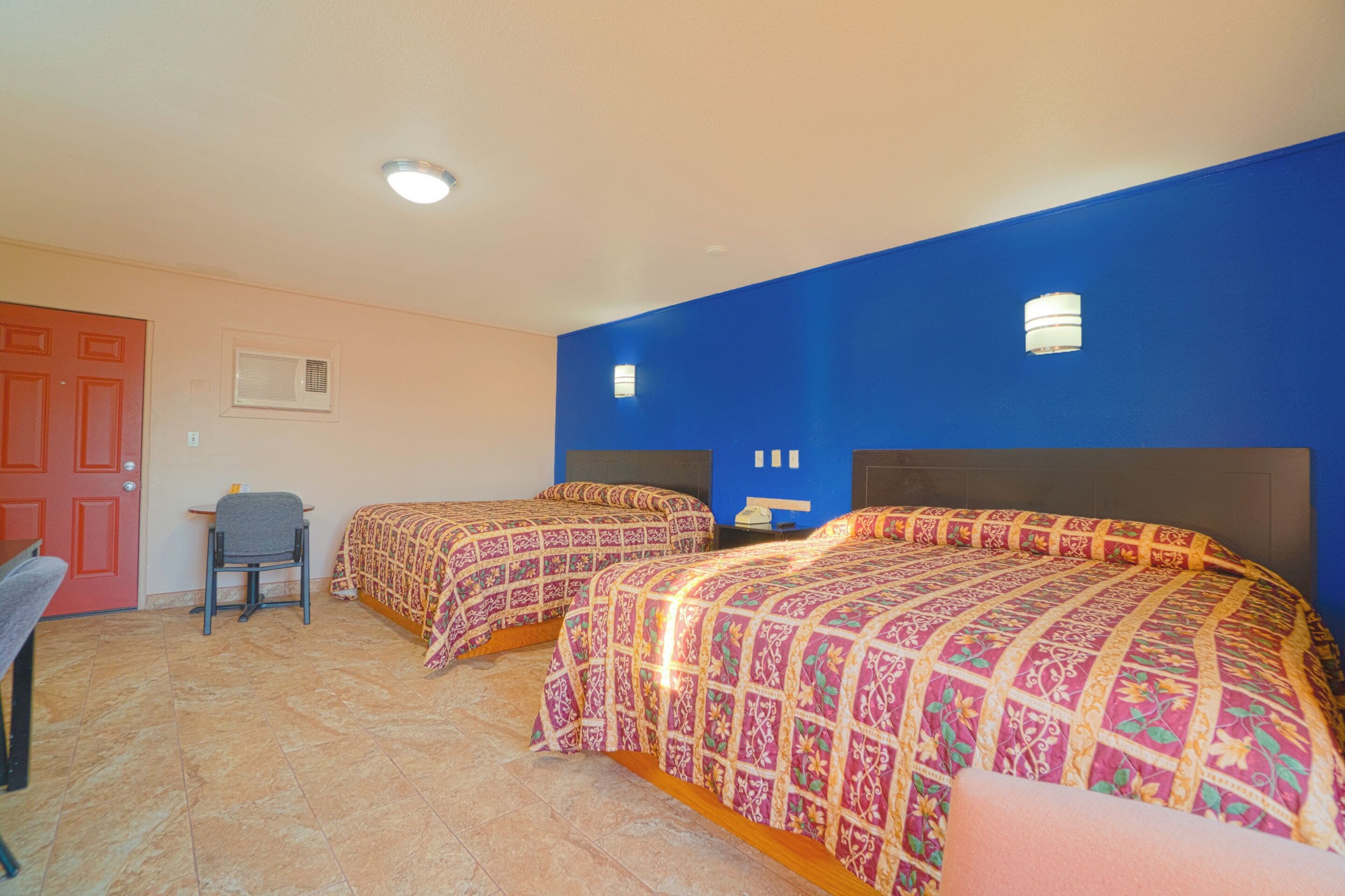 A room with two beds, a desk, and a chair.