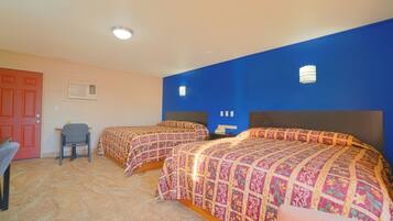 A room with two beds, a desk, and a chair.