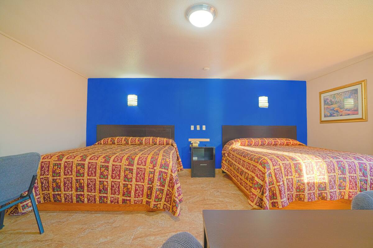 Habitación de hotel con dos camas, un escritorio y una silla.