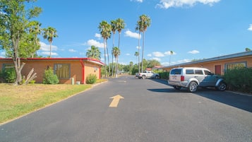 A street with a clear road marked with an arrow, surrounded by buildings and palm trees.
