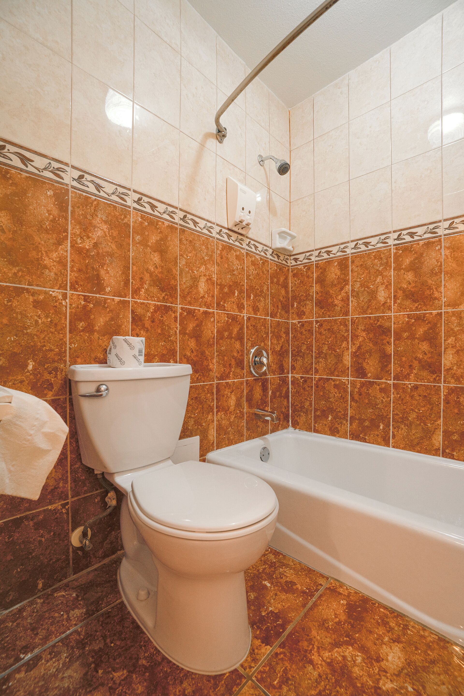 Un baño con inodoro, bañera y paredes de azulejos.