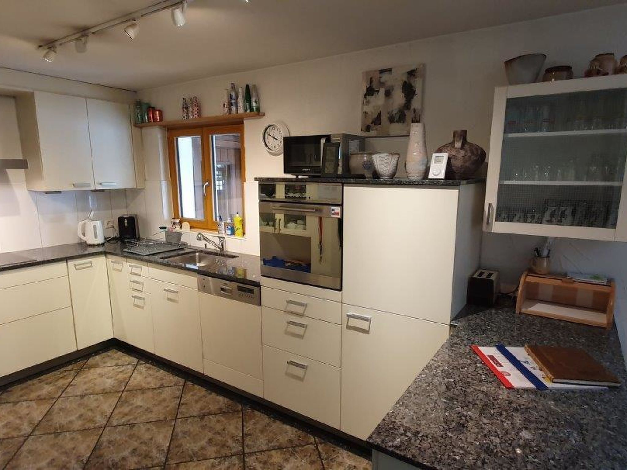 A kitchen with white cabinets, a granite countertop, a microwave, and a sink.