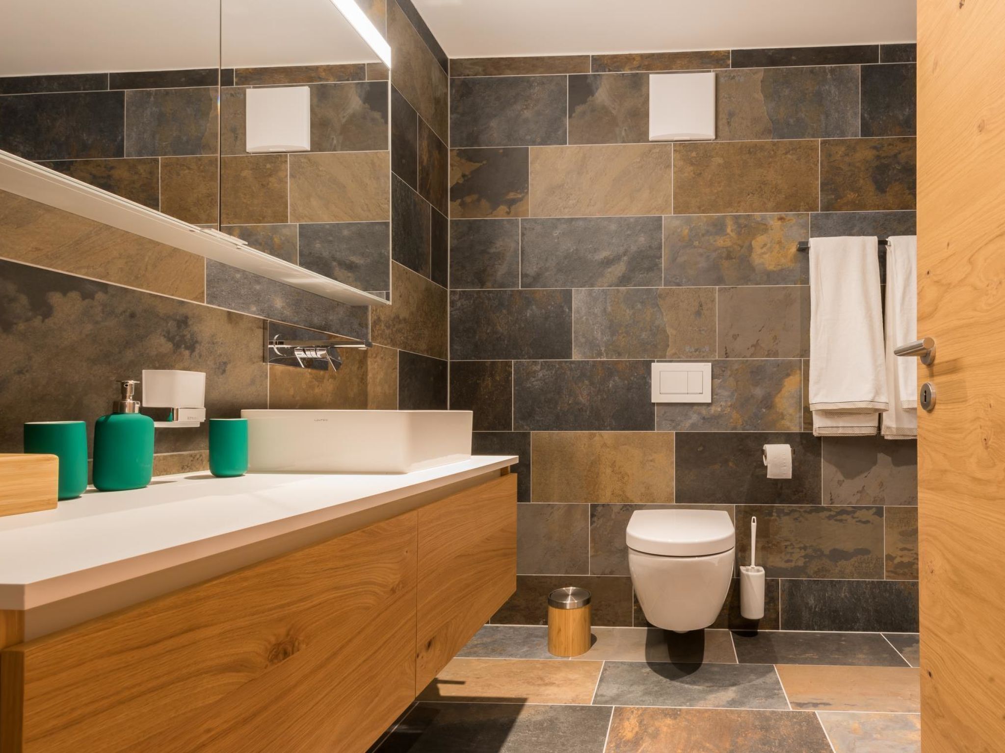 Une salle de bain moderne avec un meuble-lavabo en bois, un grand miroir et des toilettes.