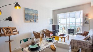 Un salon moderne avec une table à manger pour deux personnes, un canapé et un balcon offrant une vue agréable.