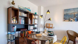 Un coin repas avec une table ronde, des chaises, une bibliothèque et un tableau accroché au mur.