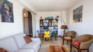 Un salon comprenant un canapé, des fauteuils, une table basse, une bibliothèque et des œuvres d’art accrochées aux murs.