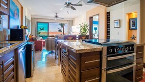 A modern kitchen with a central island, built-in oven, and ceiling fans.