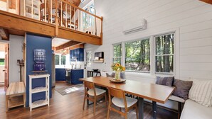 A spacious kitchen with a wooden dining table, a built-in bench, and a view of the outdoors through large windows.