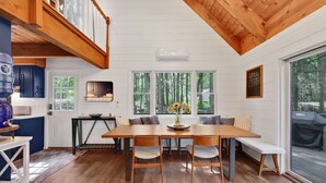 A dining area with a wooden table and chairs, a vase with flowers, and a bench. - Cozy Berkshires Lakefront Cottage! NEW (Tolland)