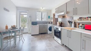 Moderni keittiö, jossa on ruokailutila, integroidut kodinkoneet ja näkymä ulos.