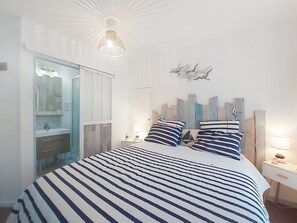 Une chambre à coucher comprenant un lit, des tables de chevet, un miroir et un luminaire au plafond.