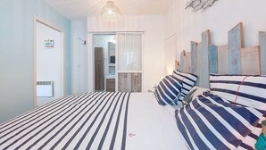 Makuuhuoneessa on kaksi sänkyä, kattovalaisin, peili ja ovi.