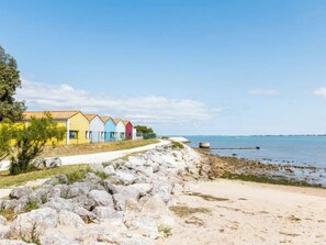 A row of colorful beach huts along a rocky shoreline with a clear view of the sea. - Les Rosiers by Interhome (Arvert)