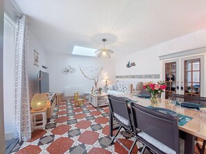 Un espace repas doté d’un sol à motifs géométriques, d’une table à manger avec des chaises, d’un lustre et d’un buffet aux portes vitrées.