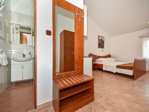 Ein Schlafzimmer mit Bett, Holzschrank und Badezimmer mit Waschbecken und Spiegel.