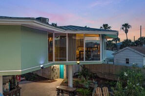 A modern house with a large glass window, a covered patio, and a well-maintained garden.