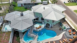 Una amplia casa con piscina, varias terrazas y zonas de estar al aire libre.