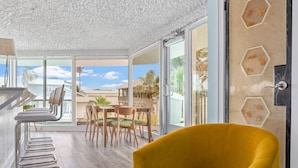 Un sillón amarillo brillante en una habitación con un ventanal grande, una mesa de madera y sillas.