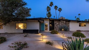 A modern house with a stone facade, large windows, and a well-lit entrance.