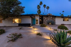 A modern house with a stone facade, a front door, and a well-lit entrance.