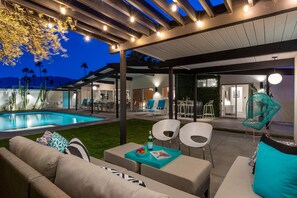 An outdoor patio with a pool, seating area, and a covered section with chairs and tables. - Aqua House - Luxury Midcentury Pool Retreat (Palm Springs)