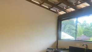 A kitchen with a wooden table and chairs, a stove, and a window with a view of greenery. - Pousada Cachoeira do Sol (Taquaraçu de Minas)