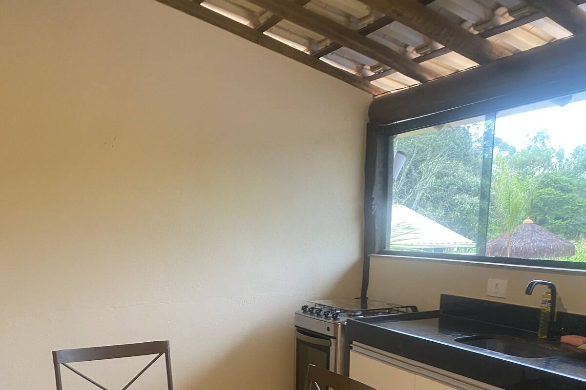Una cocina con una mesa y sillas de madera, estufa y ventana con vistas a zonas verdes.