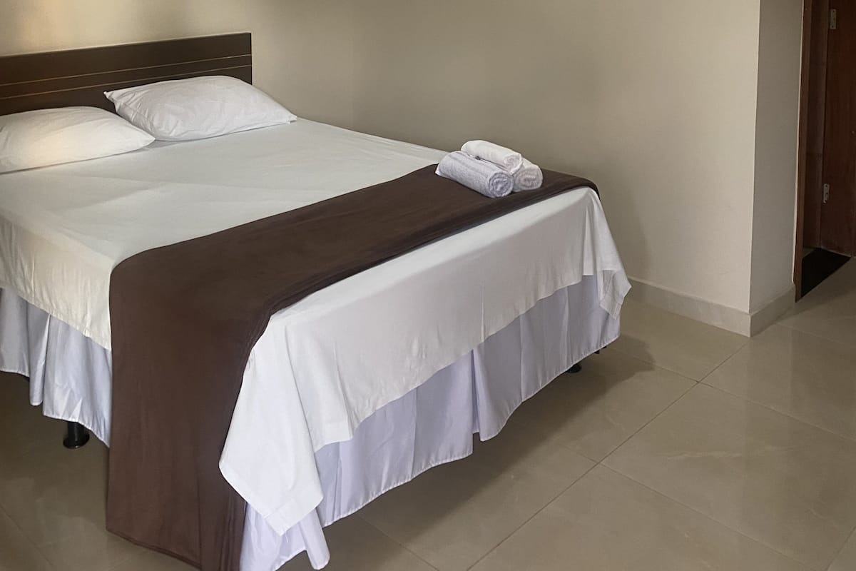 Una habitación de hotel con una cama, un ventilador de techo y una lámpara.