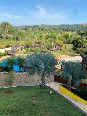 Un complexe hôtelier doté d’une piscine, de palmiers et de bungalows aux toits de chaume.