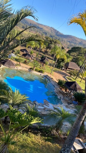 A swimming pool surrounded by tropical vegetation and a mountain backdrop.