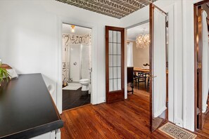 Stunning hallway with a wooden floor, leading to a dining area with a black countertop and a door to another room.
