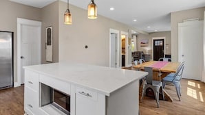 Una cocina moderna con armarios blancos, una isla central e iluminación colgante.