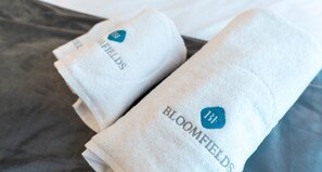 Neatly folded towels with the text "BLOOMFIELDS" and a logo. - Executive 1 BR in Oasis - 2 (Abu Dhabi)
