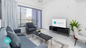 Een moderne woonkamer met een bank, fauteuils, een salontafel, een televisie en een potplant.